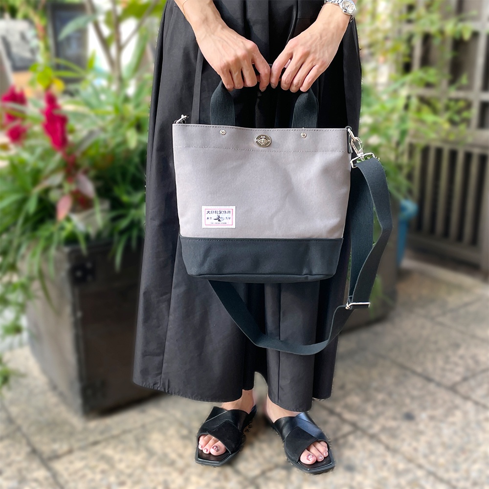 犬印純棉帆布兩用雙色托特包，採用淺灰色與炭黑色拼接設計，配有品牌標籤，可手提或肩背。