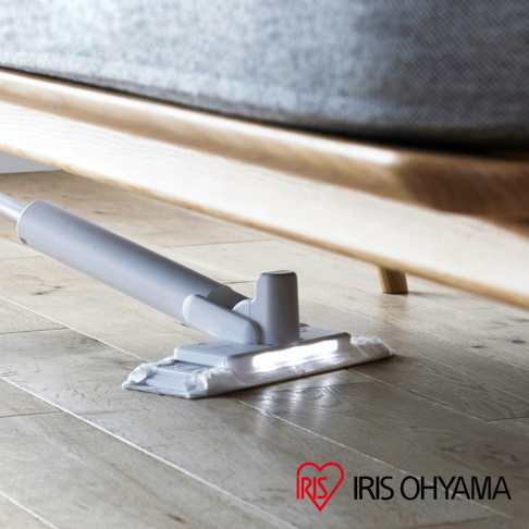 淺灰色電動平板拖把，配有LED照明，正在清潔木質地板下方的空間，拖把頭採用白色布墊。