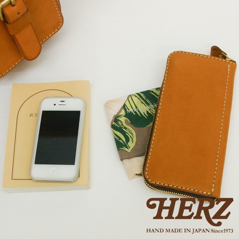 職人手作皮革長夾，採用天然皮革製作，呈現溫潤的焦糖色澤，搭配精緻的縫線與俐落的拉鍊設計，展現簡約實用的風格。