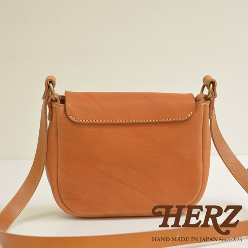 職人手作皮革鹿角扣繩肩背包，採用天然棕色皮革，附有可調節的皮革肩帶，簡約設計，展現細緻縫線工藝。