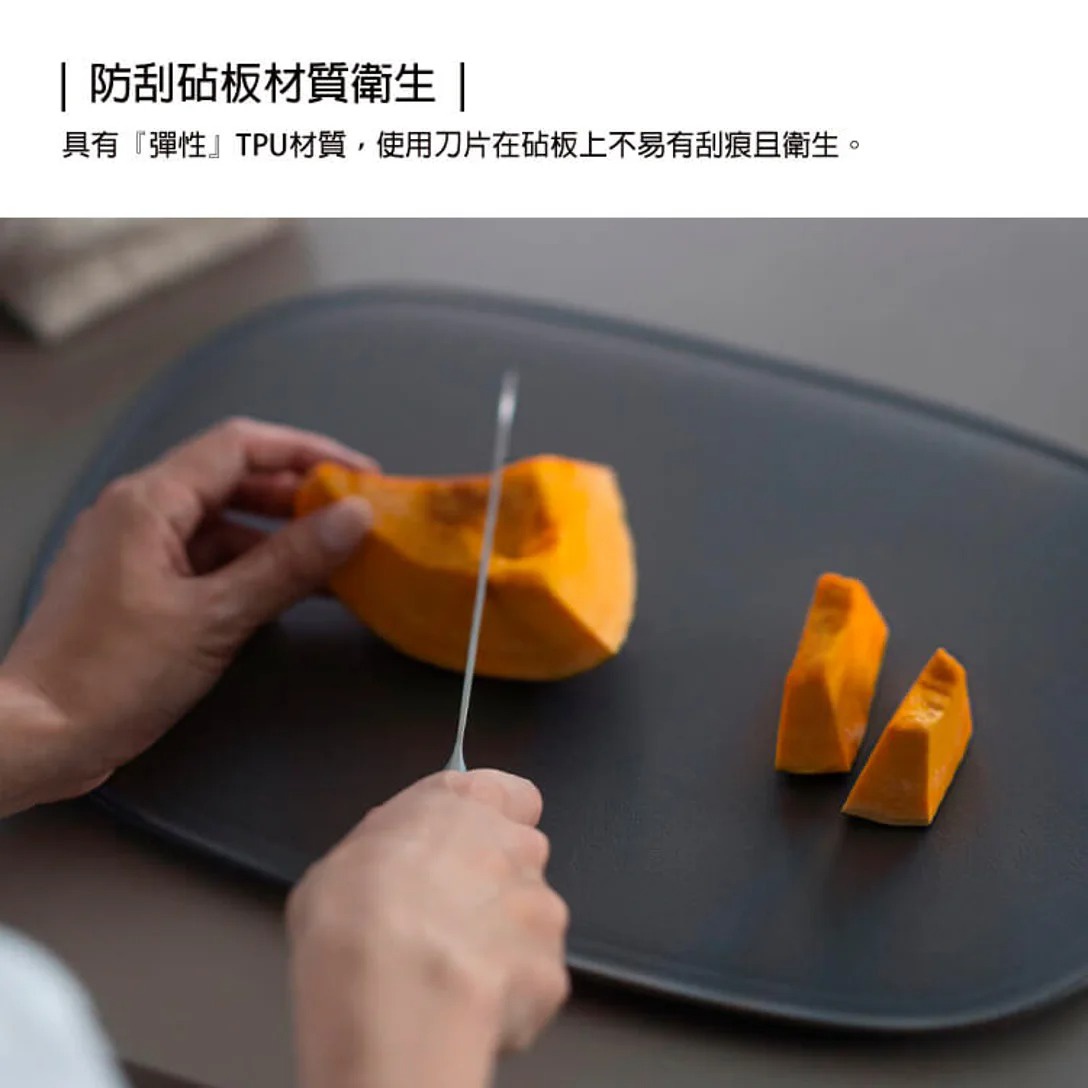 一個人正在使用刀在黑色砧板上切南瓜，砧板上已有兩塊切好的南瓜。