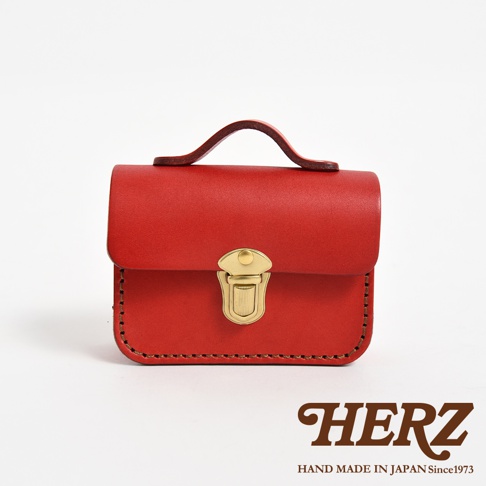 紅色職人手作皮革迷你收納包，設有金色金屬鎖扣與提把，包身以縫線裝飾。