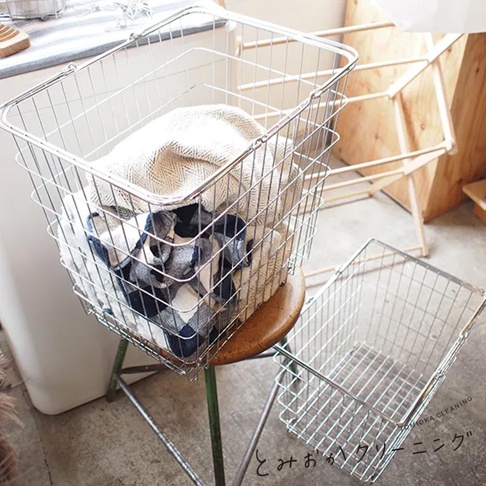 兩個銀色不鏽鋼網格收納籃，其中一個籃子裡裝有白色和藍色格紋的布料，以及一條米白色紋路織物的毛巾。