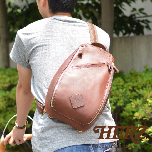 職人手作皮革多功能收納斜背包，採用棕色皮革材質，設計簡約，配有拉鍊開合和可調節肩帶，適合日常攜帶。
