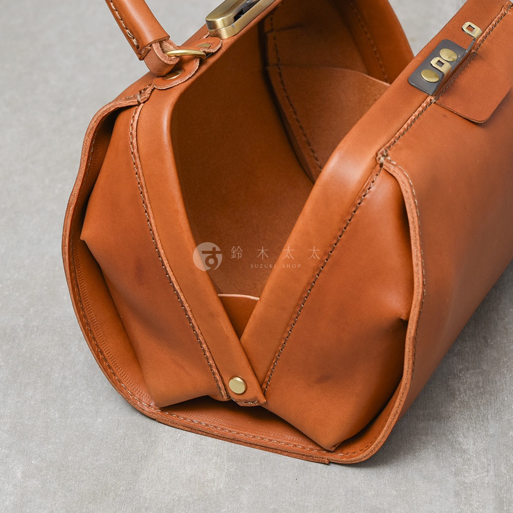 職人手作皮革Organ兩用口金手提包，棕色牛皮材質，設有金屬旋轉鎖扣及提把，包身縫線清晰，內部結構可見。