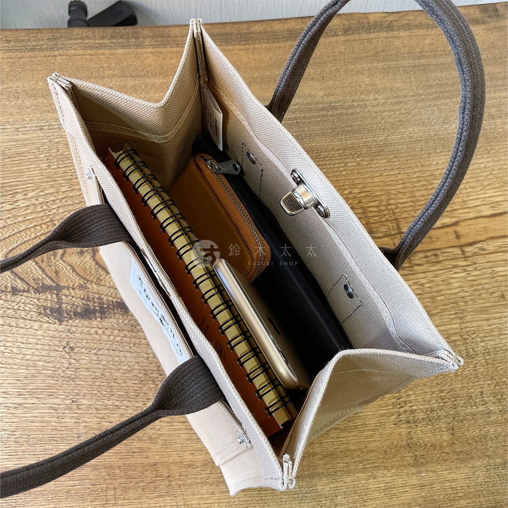 犬印純棉帆布迷你托特包，米白色帆布材質，搭配深棕色提把。包內裝有筆記本、手機、錢包，展示其收納空間。