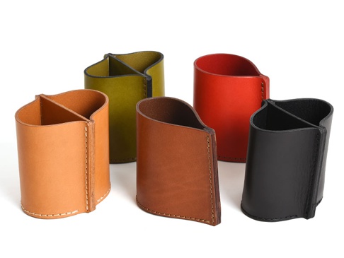五個職人手作皮革分隔筆筒，分別為淺棕色、深棕色、綠色、紅色及黑色。筆筒為圓柱形，頂部有兩個分隔，皮革表面平滑，邊緣以白色縫線勾勒。