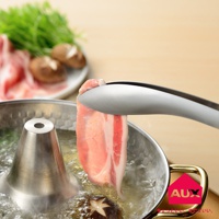 銀色金屬材質的分菜夾夾著一片生豬肉，正在放入一個冒著熱氣的鍋中，鍋內有水、香菇和蔬菜。