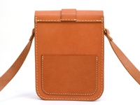 棕色皮革製作的單肩包，有經典皮扣和外接小口袋，邊緣縫線明顯，附有皮革肩帶。