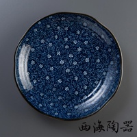 深藍色陶瓷圓盤，飾有白色小花與迴紋圖案，盤緣帶有金邊，整體呈現日式美濃燒風格。