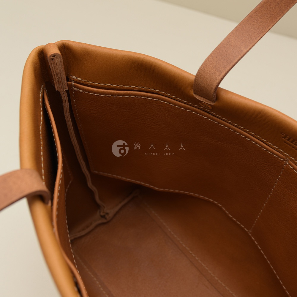 職人手作皮革托特包內部，展示四個開放式口袋，皮革材質呈現溫潤的棕色調，車縫線清晰，包身簡潔。