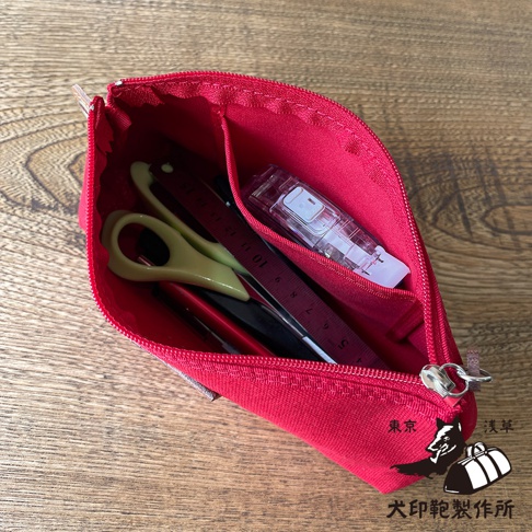 紅色石洗帆布小物收納包，內部裝有綠色剪刀、紅色筆、黑色筆、尺和修正帶。