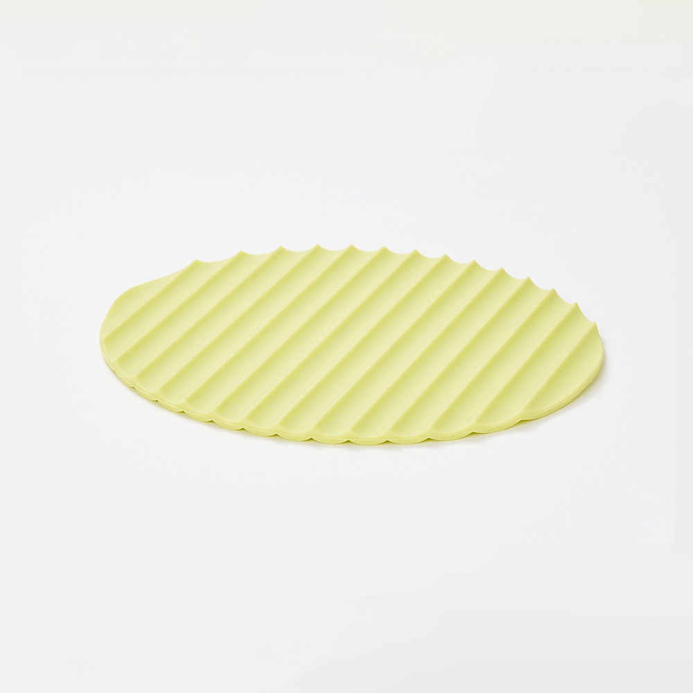 淺綠色橢圓形隔熱墊，表面佈滿平行凹槽紋理，邊緣帶有波浪狀鋸齒。