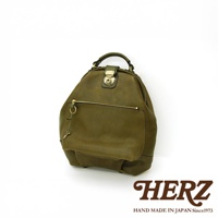 職人手作皮革輕旅行後背包 R-144，採用柔軟質感的皮革製成，呈現復古的墨綠色調。包款設有頂部提把、前方拉鍊口袋及翻蓋鎖扣，簡潔實用的設計適合日常或短途旅行。