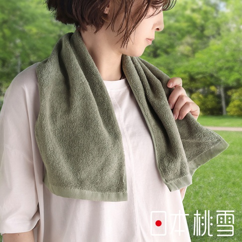 穿著白色T恤的女子，肩上披著一條淺綠色毛巾，背景為模糊的綠色樹木，右下角有「日本桃雪」的文字標記。