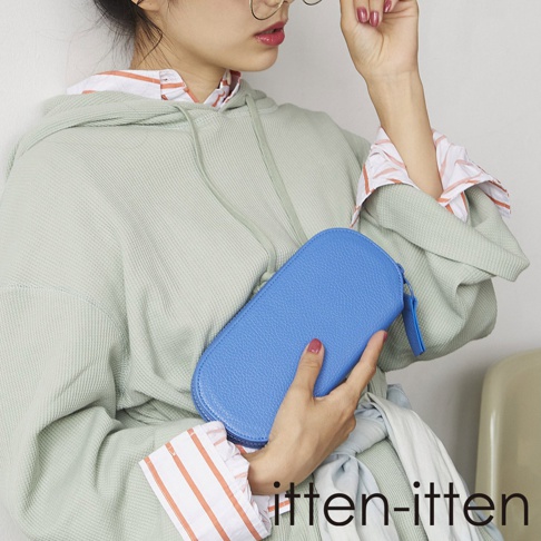 itten-itten 品牌標誌，一名女子拿著亮藍色皮革長夾，身穿淺綠色帽T與條紋襯衫。