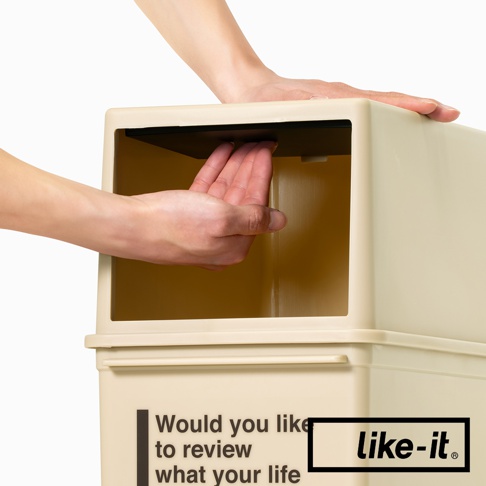 奶油色塑膠前開式高版可疊垃圾桶，展示手部操作內部黑色擋板，垃圾桶上有英文文字與like-it品牌標誌。