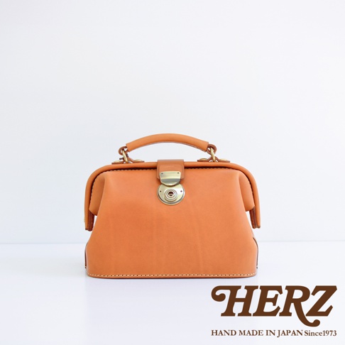 職人手作皮革方型迷你醫生包，呈現溫潤的淺棕色皮革，搭配復古金色旋轉鎖扣與金屬配件，簡約設計展現質感。