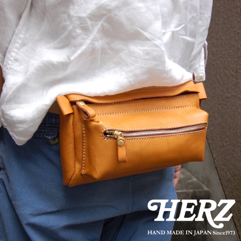 職人手作皮革兩用腰掛斜背包，深棕色皮革，附有拉鍊主袋和前置拉鍊袋，車縫線清晰，適合腰掛或斜背。