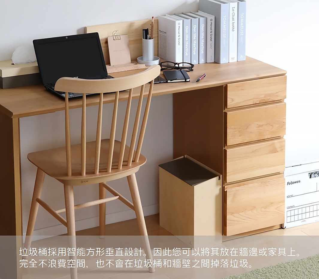 一張木質書桌旁，擺放著一張木質餐椅、一台筆記型電腦、幾本書籍和一個淺米色的掀蓋式小容量垃圾桶，垃圾桶的內蓋為深灰色。