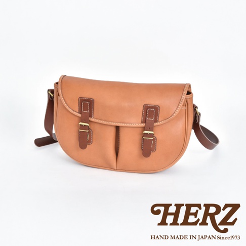 職人手作皮革傳統釣魚包，採用天然皮革製作，經典的馬鞍包造型，帶有兩個皮帶扣的翻蓋設計，顏色為溫潤的棕褐色，適合日常或戶外使用。