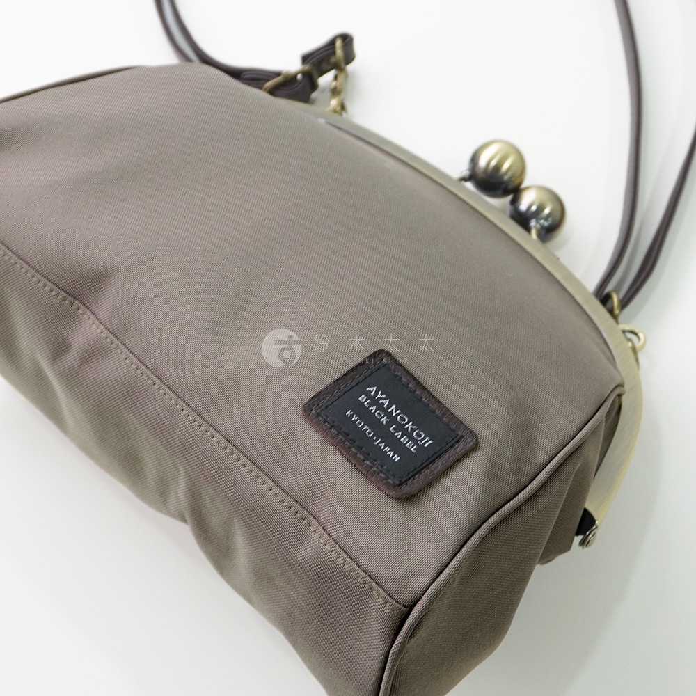 一灰色斜背包，特寫品牌標籤，標籤上印有 AYANOKOJI BLACK LABEL KYOTO, JAPAN 字樣。