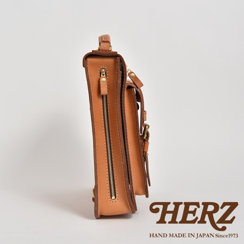 側邊視角的淺棕色皮革三用後背包，展示其側邊拉鍊、金屬扣環及皮革材質。