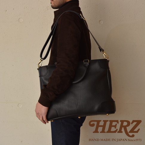 職人手作皮革Organ兩用商務托特包，黑色皮革材質，設有頂部提把及可拆卸肩帶，包身有金屬腳釘裝飾。