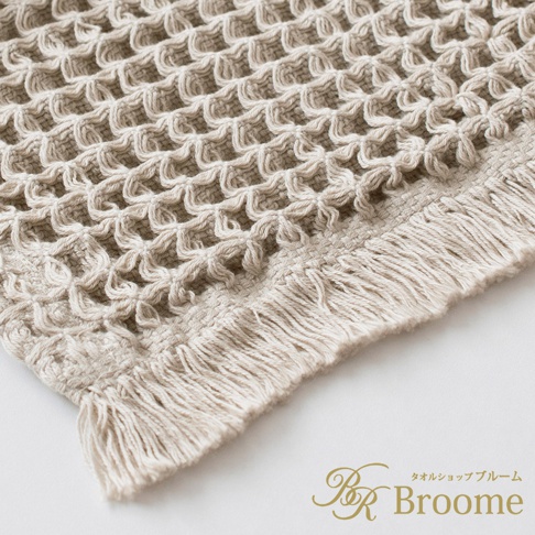 米白色的今治鬆餅浴墊，以立體網格編織紋理呈現，邊緣帶有流蘇裝飾，材質為柔軟的棉質。