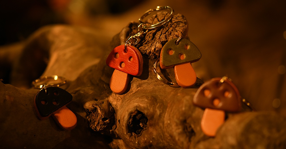 職人手作皮革香菇造型鑰匙圈，有紅色、綠色、黑色及棕色等四種顏色，每個鑰匙圈皆由皮革製成，造型獨特，附有金屬鑰匙環。