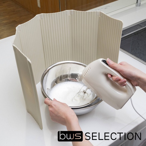 淺米色六片式摺疊隔板，帶有直條紋紋理，圍繞著一個裝有打發液體的銀色金屬攪拌盆。左側有一隻手拿著攪拌盆，右側有一隻手握著白色電動打蛋器。