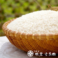 編織籃盛滿飽滿的白色越光米，背景是模糊的綠色植物。