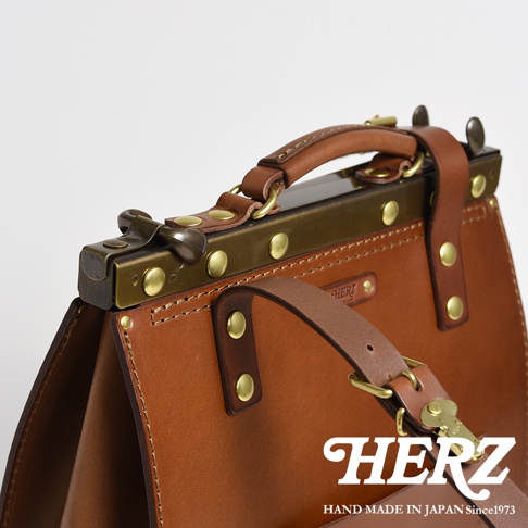 皮革復古口金後背包，採用棕色皮革和黃銅色五金件，搭配手提帶和肩帶。