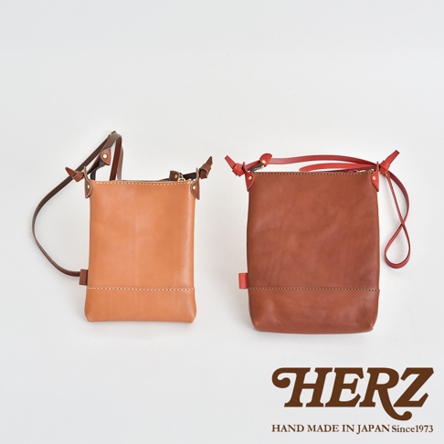 職人手作皮革直式隨身單肩包，左側為淺褐色皮革，右側為深褐色皮革，兩款包皆為直向方形設計，配有可調節式皮革背帶及拉鍊開口，展現簡約質感。