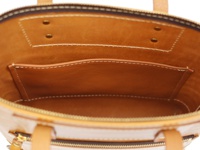 職人手作皮革威靈頓直式拉鍊托特包內部，展現光滑的淺棕色皮革內襯，設有對稱的縫線口袋和兩個金屬扣眼。包體外層為帶有光澤的淺棕色皮革，搭配金色拉鍊和皮革提把。