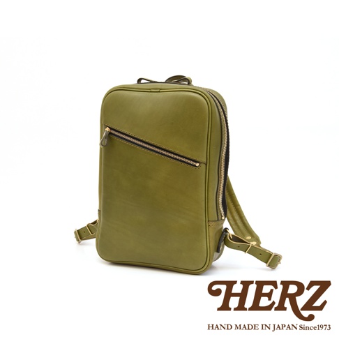 橄欖綠皮革長方型後背包，正面有一個斜向拉鍊口袋，頂部有提把，兩側有可調節肩帶。