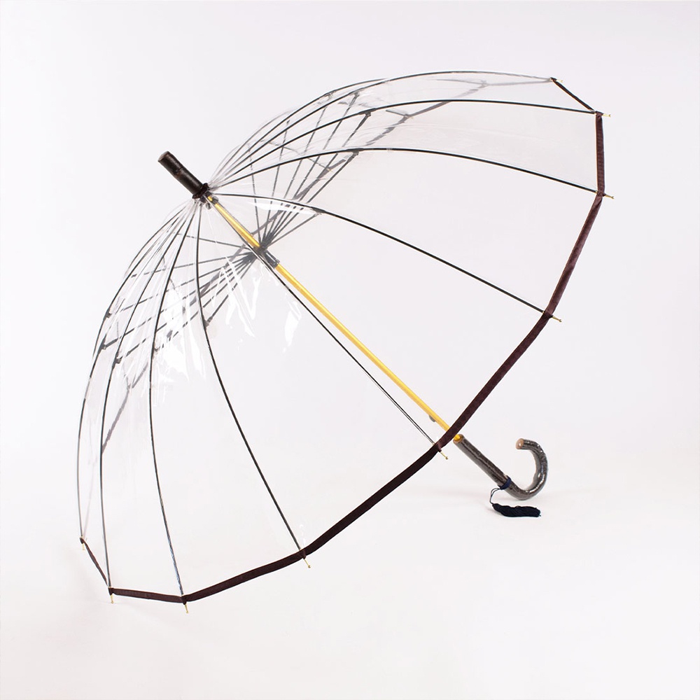 一把透明傘，傘面為高品質塑膠材質，傘骨與傘柄為樺木製成，傘緣以深棕色布條包邊，傘柄呈現彎曲狀，傘下繫有一黑色流蘇。