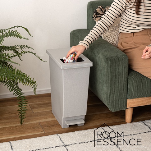 簡約風格的淺灰色 20L 垃圾桶，配有腳踏板和方形開口蓋，旁邊有一株綠葉植物和綠色沙發。