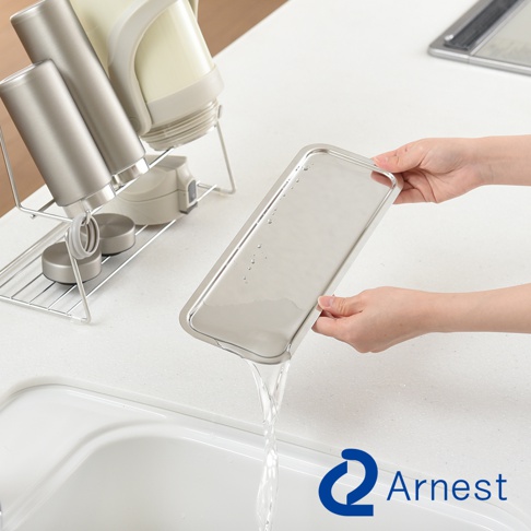 Arnest 品牌 logo 下，一隻手正將裝有水的銀色長方形托盤傾斜，水從托盤邊緣流下，旁邊的瀝水架上擺放著銀色水壺和白色熱水壺。