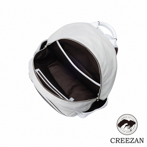 這是一款白色帆布材質的 CREEZAN 品牌大容量後背包，以俯視角度呈現包包內部結構。包內設有深色內襯，並配備獨立的夾層隔板與拉鍊袋，外觀設計簡約俐落，並於右下方標註品牌名稱與徽標。