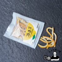 透明包裝內有金黃色澤的柑橘果皮乾，部分散落在黑色背景上，果皮呈現彎曲條狀，表面帶有結晶糖粒，包裝上有日文標示與黃色柑橘圖案。