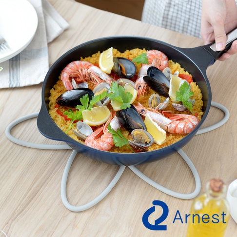 鍋具防刮保護墊，淺灰色矽膠材質，呈現環狀設計，用於支撐裝有海鮮飯的藍色平底鍋。