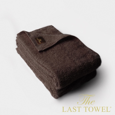 一組兩條深棕色純棉毛巾，表面柔軟蓬鬆，帶有品牌標籤。