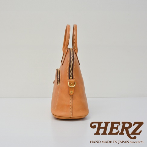 職人手作皮革兩用經典貝殼手提包，淺棕色，皮革材質，設有拉鍊開合和側邊拉鍊口袋，配有短提把和可拆卸肩帶的金屬扣環。