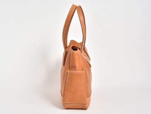 淺棕色皮革橫式肩背托特包，側面視角，有提把和外側口袋，車縫線清晰可見。