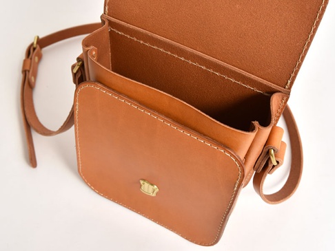 棕色皮革翻蓋迷你單肩包，頂部翻蓋開啟，露出內部隔層，搭配可調節肩帶和金色金屬扣。
