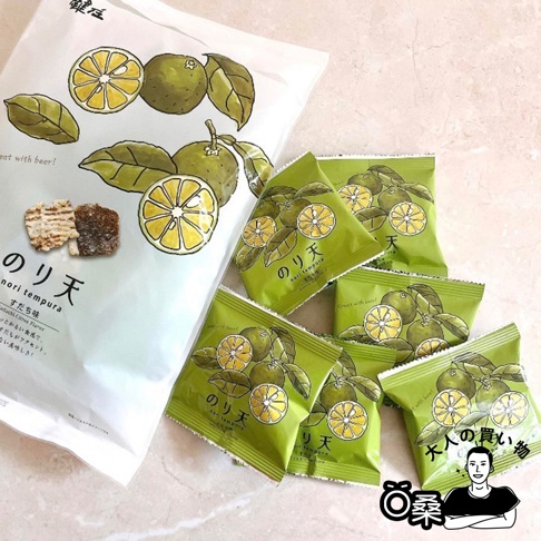 一包白色包裝的海苔天婦羅餅乾，印有綠色柑橘與葉子的插畫，旁邊散落著數個綠色小包裝的海苔天婦羅餅乾，同樣印有柑橘與葉子圖案。