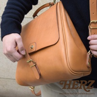 職人手作皮革屋瓦風後背包 R-15，採天然皮革製成，呈現溫潤的棕褐色。包款設計簡約，配有黃銅色金屬扣環及可調節式皮質背帶，展現復古風格。