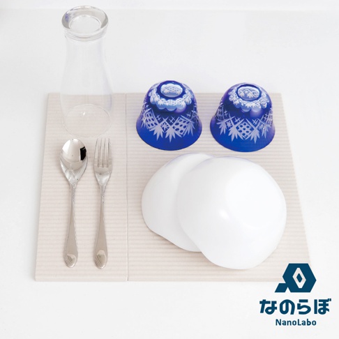 NANOLABO 的珪藻土防潮塊與吸水置物墊組合，包含藍色花紋玻璃杯、金屬餐具與玻璃瓶。