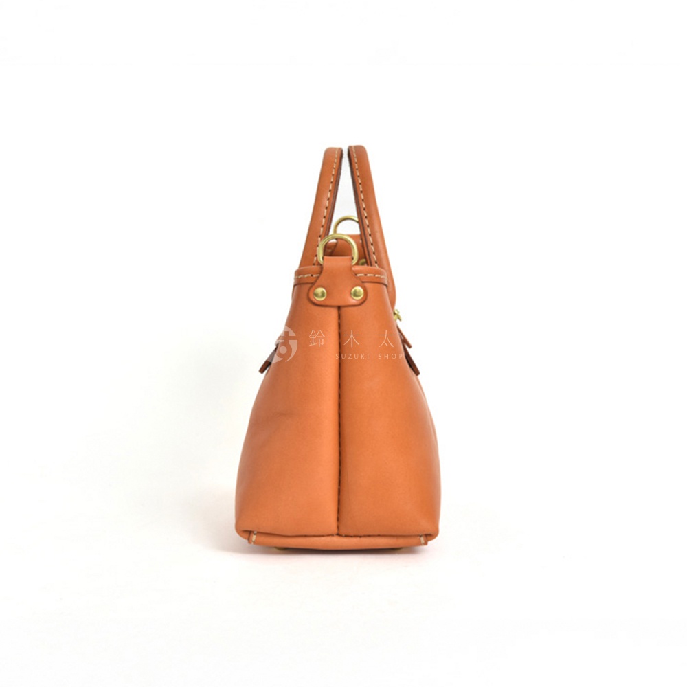 職人手作皮革迷你托特包，採用鞣製皮革製成，呈現自然的棕褐色。包身線條簡潔，配有雙提把和金屬扣環，展現經典風格。